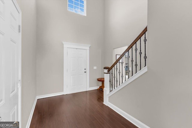 foyer entrance featuring dark wood finished floors, baseboards, and stairs