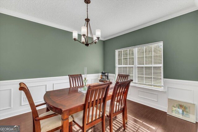 732 Waterlily Ct, Hinesville, GA 31313 - dining area featuring an inviting chandelier, dark wood-style flooring, a wainscoted wall, ornamental molding, and a textured ceiling