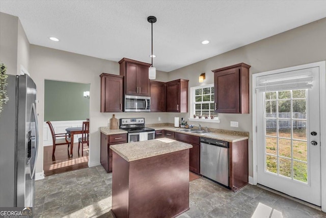 kitchen featuring stainless steel appliances, a sink, light countertops, a center island, and pendant lighting