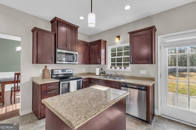 kitchen featuring a kitchen island, appliances with stainless steel finishes, decorative light fixtures, a healthy amount of sunlight, and a sink