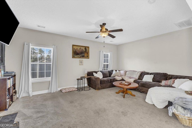 carpeted living area with a ceiling fan, visible vents, a textured ceiling, and baseboards