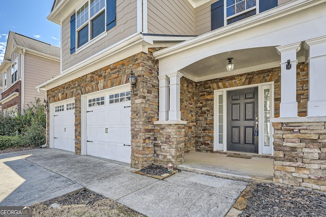 property entrance with stone siding, covered porch, an attached garage, and concrete driveway