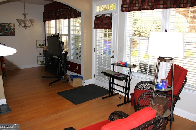 workout area with arched walkways, baseboards, a chandelier, and wood finished floors