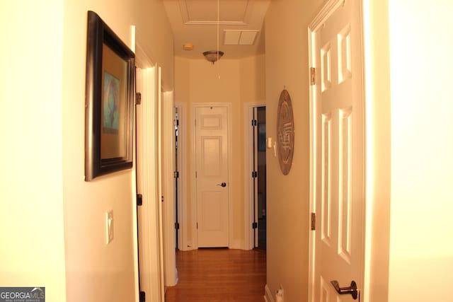 corridor with attic access and wood finished floors