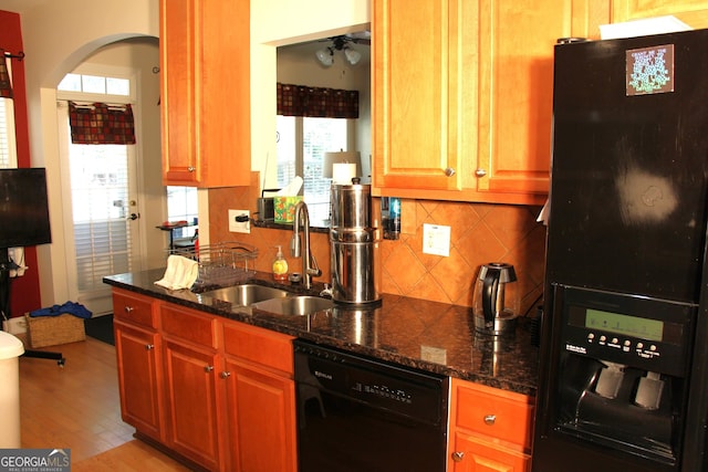 kitchen with a wealth of natural light, a sink, light wood finished floors, and black appliances