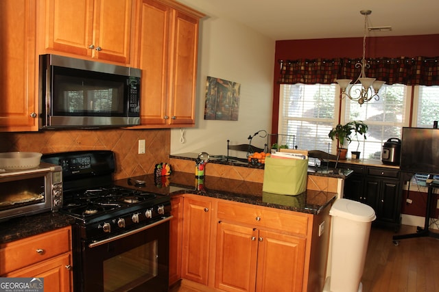 kitchen featuring decorative backsplash, stainless steel microwave, brown cabinets, a peninsula, and black range with gas stovetop