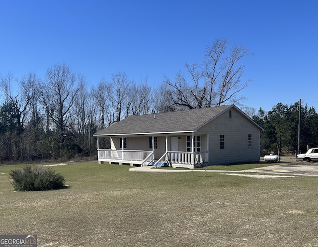 view of front facade with a shingled roof, a porch, and a front yard