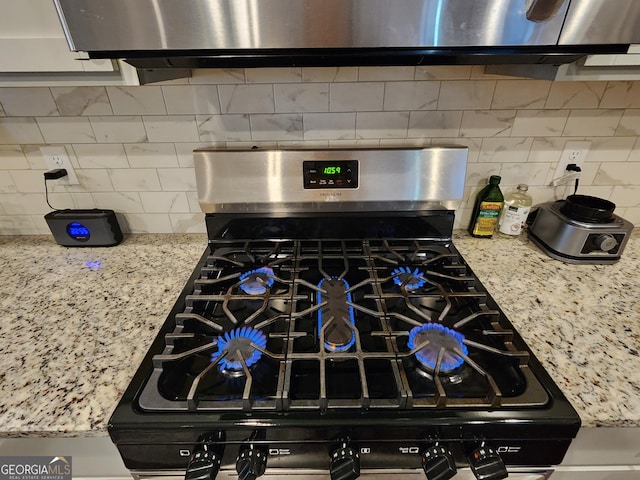 interior details with light stone countertops, gas range oven, and backsplash