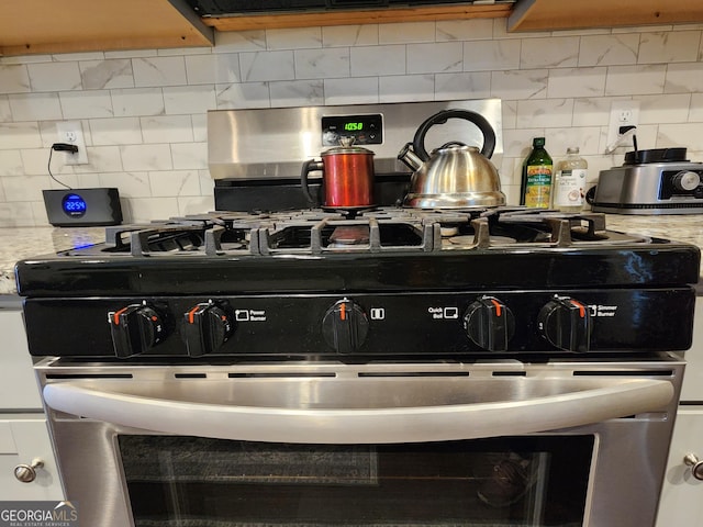 details featuring tasteful backsplash, light stone counters, and gas range