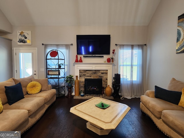 living room with dark wood-style floors, lofted ceiling, and a stone fireplace