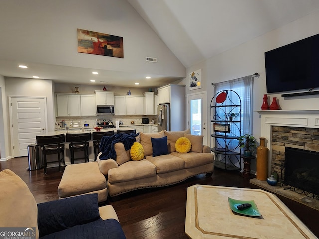 living room featuring dark wood-style floors, a fireplace, recessed lighting, visible vents, and high vaulted ceiling