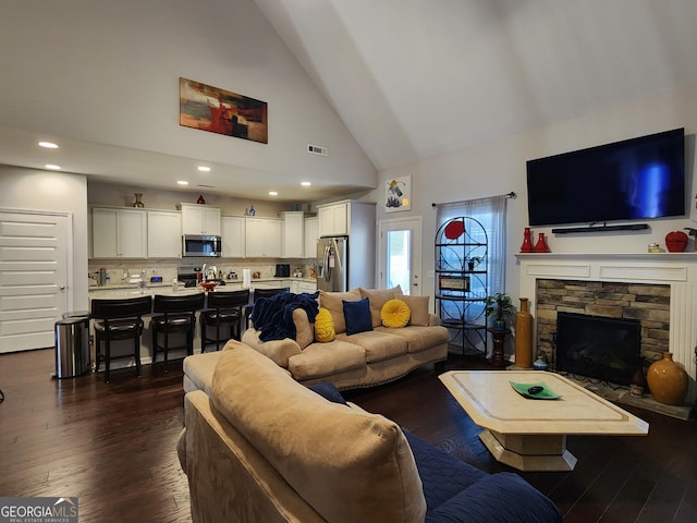 living room featuring dark wood-style floors, visible vents, a fireplace, and high vaulted ceiling