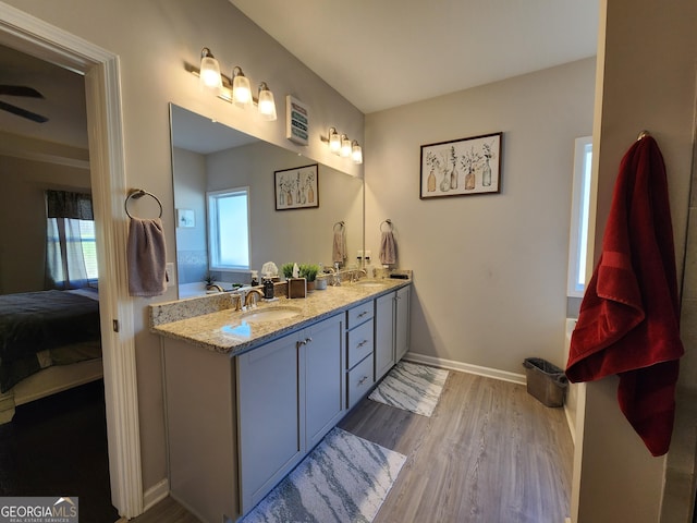 ensuite bathroom featuring double vanity, baseboards, wood finished floors, ensuite bathroom, and a sink