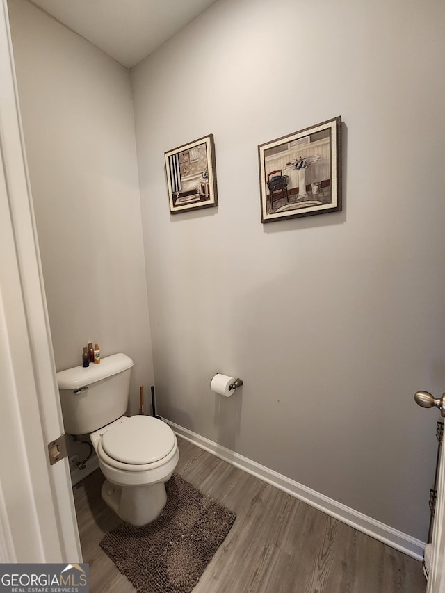 bathroom with wood finished floors, toilet, and baseboards