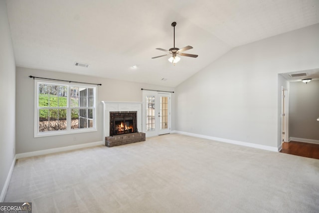 unfurnished living room featuring light colored carpet, visible vents, vaulted ceiling, and a fireplace