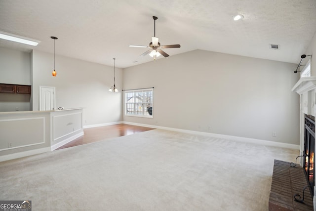 unfurnished living room featuring a fireplace, light carpet, vaulted ceiling, a textured ceiling, and ceiling fan