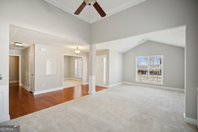 unfurnished living room with carpet, ceiling fan, wood finished floors, high vaulted ceiling, and baseboards