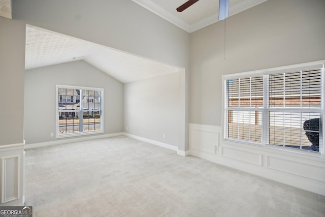 unfurnished room featuring a wainscoted wall, lofted ceiling, a decorative wall, a ceiling fan, and light carpet