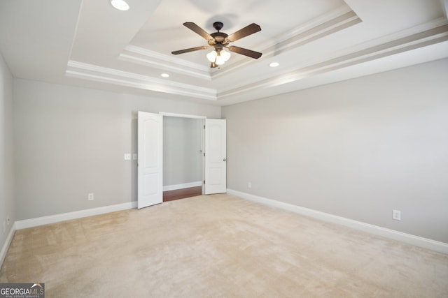 unfurnished bedroom with recessed lighting, a raised ceiling, light colored carpet, ornamental molding, and baseboards