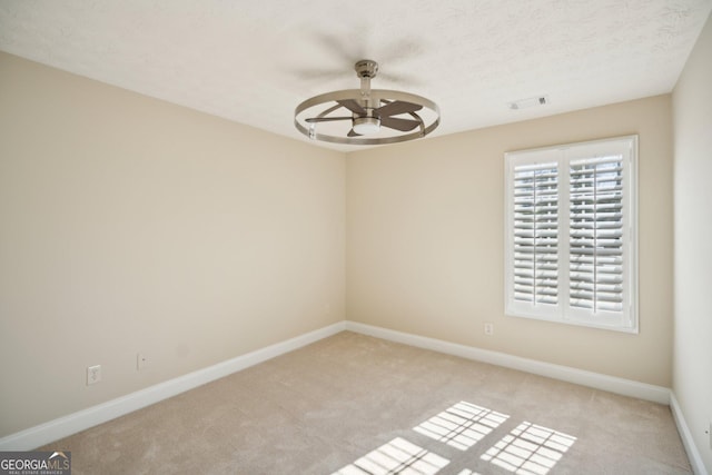 unfurnished room featuring visible vents, light carpet, ceiling fan, a textured ceiling, and baseboards