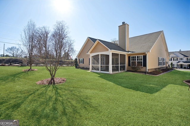 rear view of house with a sunroom, a lawn, and a chimney