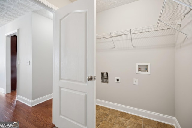 clothes washing area featuring washer hookup, hookup for an electric dryer, a textured ceiling, and baseboards