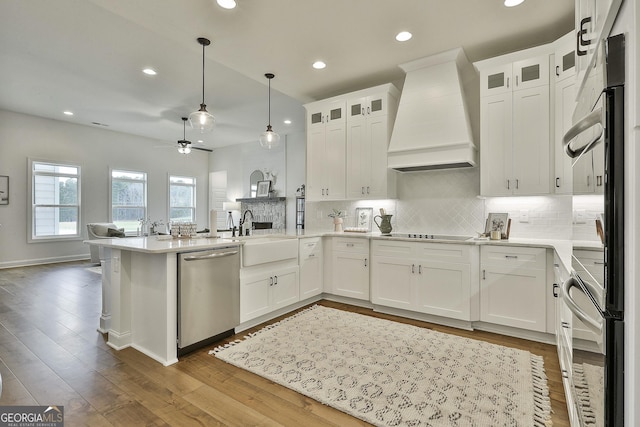 kitchen featuring dishwasher, wall chimney exhaust hood, light countertops, and white cabinetry