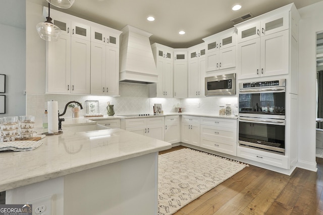 kitchen featuring white cabinets, custom range hood, glass insert cabinets, and stainless steel appliances