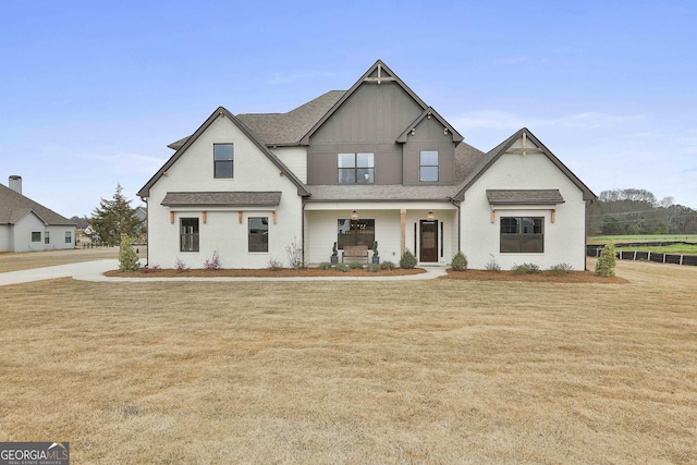 view of front of house with a porch, roof with shingles, and a front lawn