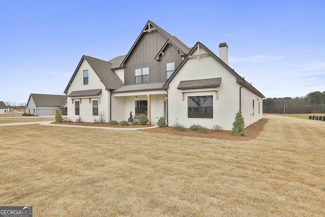 modern farmhouse featuring a shingled roof, a chimney, a front lawn, board and batten siding, and brick siding