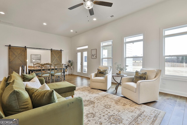 living area featuring french doors, a barn door, wood finished floors, and recessed lighting