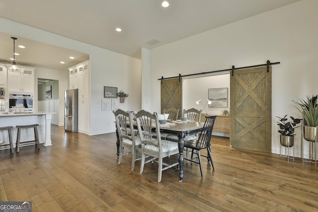 dining area featuring dark wood-style flooring, recessed lighting, visible vents, a barn door, and baseboards