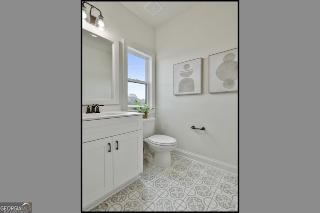 half bathroom featuring toilet, vanity, visible vents, baseboards, and tile patterned floors