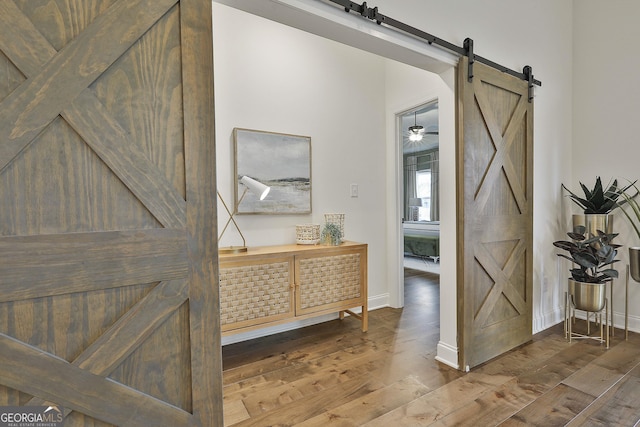 interior space featuring a barn door, wood finished floors, and baseboards