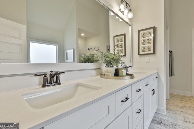 bathroom with vaulted ceiling, a sink, a tile shower, and double vanity