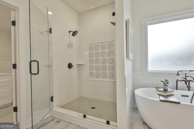 full bathroom with a shower stall, tile walls, and a freestanding bath