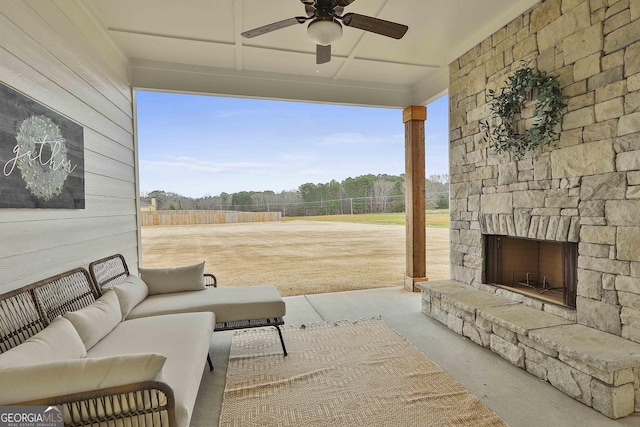 exterior space featuring a ceiling fan, a wealth of natural light, an outdoor stone fireplace, and wood walls