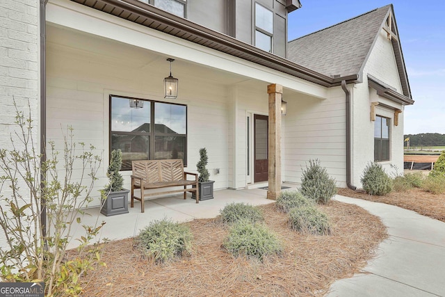 entrance to property featuring covered porch and roof with shingles