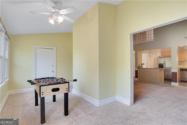 game room featuring high vaulted ceiling, light carpet, baseboards, and a ceiling fan