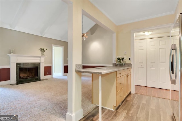 kitchen with freestanding refrigerator, light countertops, light wood-type flooring, light brown cabinets, and a high end fireplace