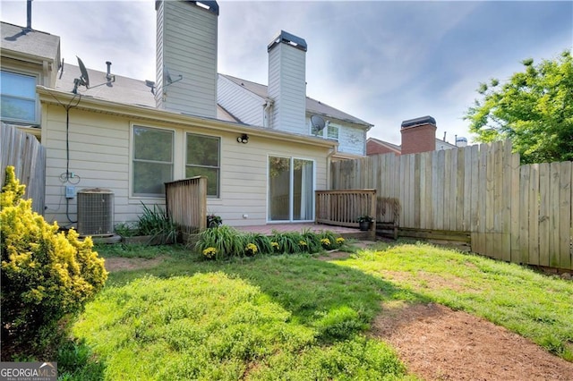 rear view of house featuring a chimney, cooling unit, a lawn, and fence