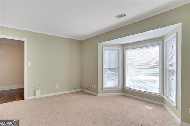 empty room featuring light carpet, visible vents, baseboards, and ornamental molding