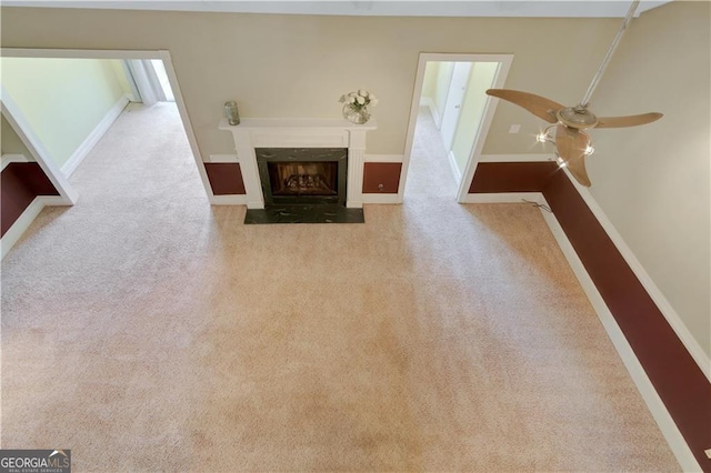 unfurnished living room with a fireplace with flush hearth, light carpet, baseboards, and a ceiling fan