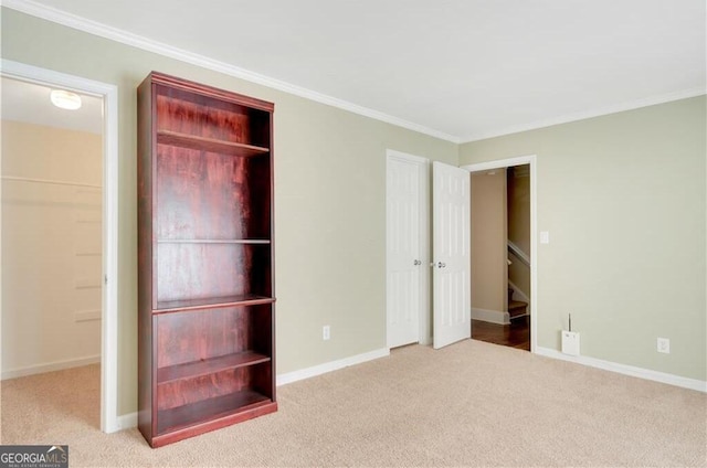 unfurnished bedroom featuring ornamental molding, light colored carpet, and baseboards