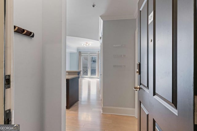 entrance foyer with ornamental molding, light wood-style flooring, and baseboards