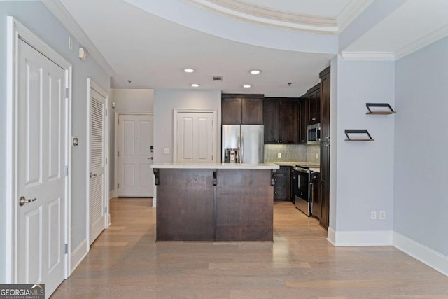 kitchen with tasteful backsplash, appliances with stainless steel finishes, a center island, light countertops, and crown molding