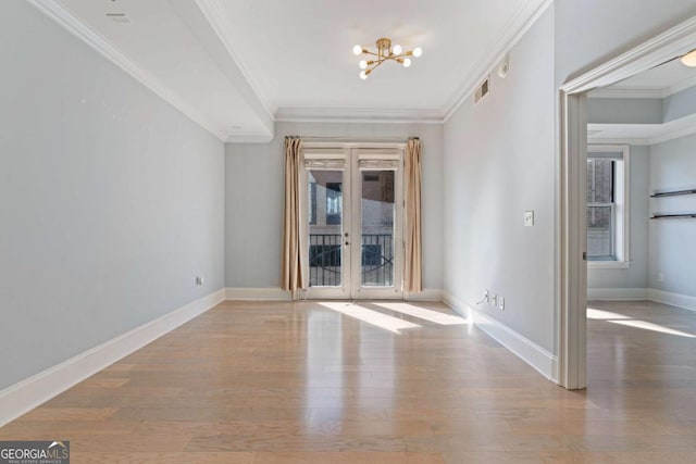 spare room with light wood-type flooring, plenty of natural light, visible vents, and ornamental molding