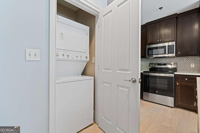 laundry room featuring stacked washer and dryer, light wood-type flooring, and laundry area