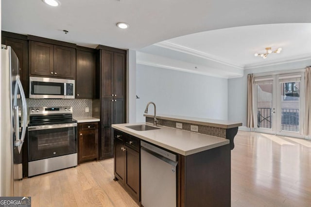 kitchen with dark brown cabinets, appliances with stainless steel finishes, a sink, and a center island with sink