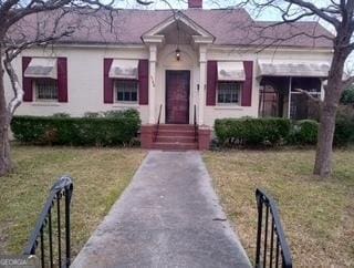 view of front of property with a chimney and a front lawn